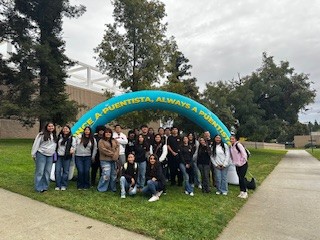 Group of students posing together outdoors in front of a colorful Napa Valley College sign that reads “Once a Puentista, Always a Puentista.”